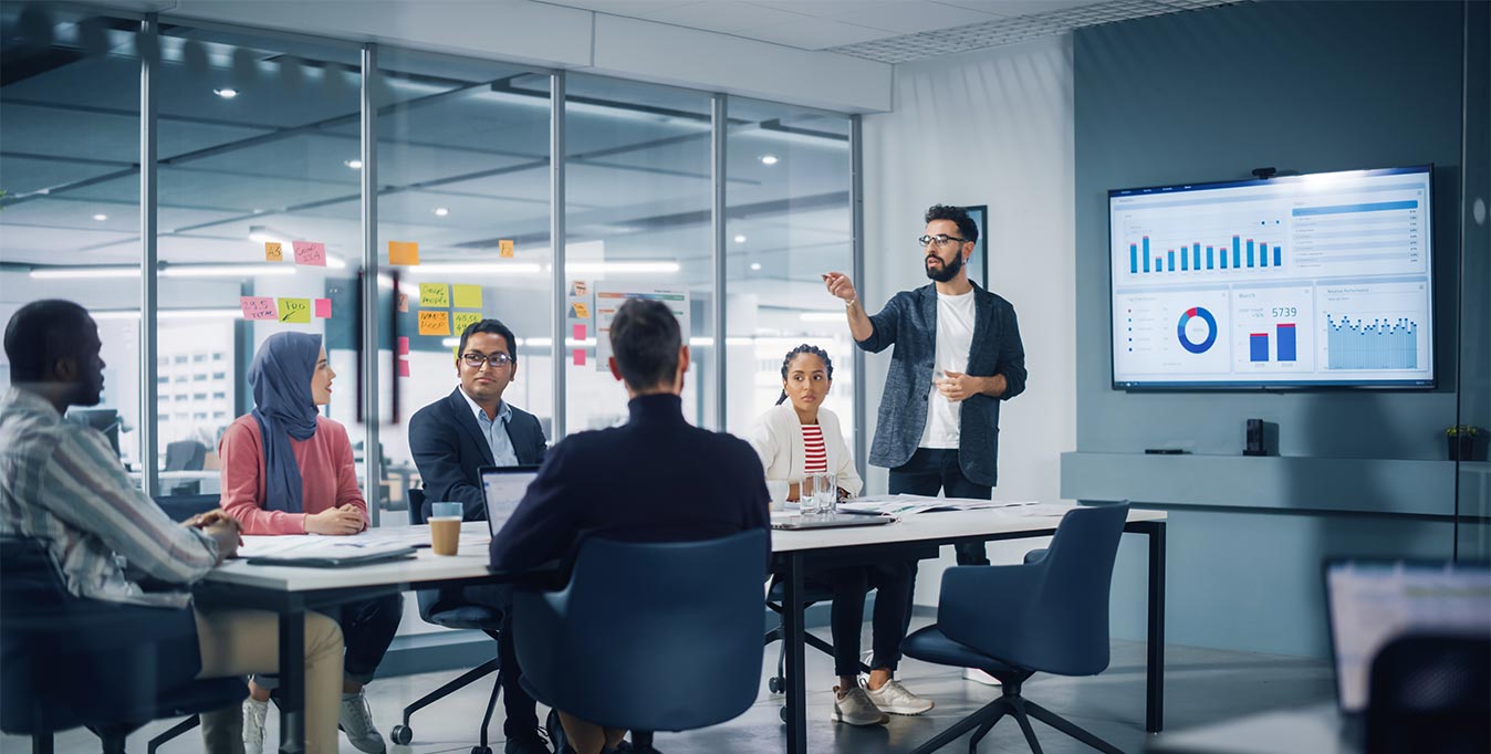 Group of people in a meeting room looking at a presentation on screen