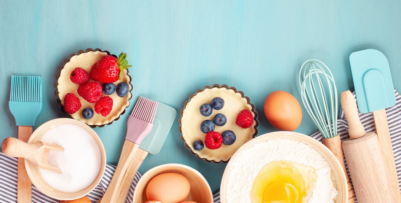 Baking utensils and cooking ingredients for tarts, cookies, dough and pastry. Flat lay with eggs, flour, sugar, berries.
